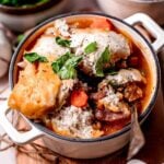 homemade vegan beef stew topped with biscuits in a white pot.