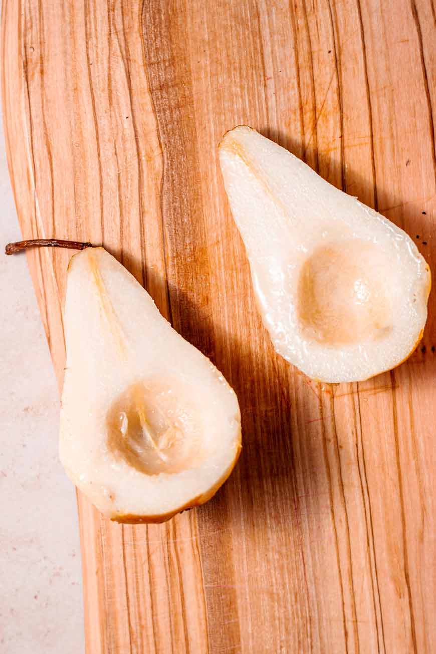 cored pears on a wooden cutting board.