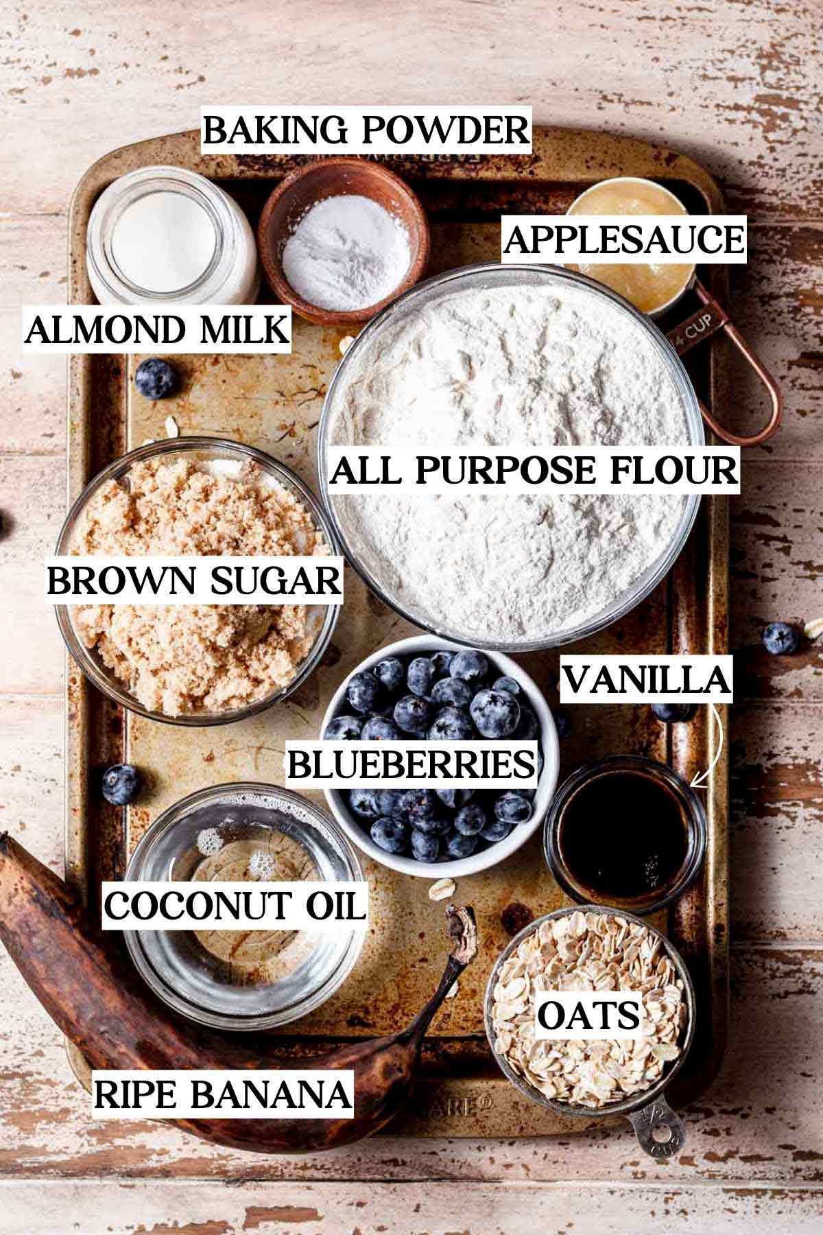 ingredients like bananas, blueberries, oatmeal and coconut oil on a rustic metal baking tray.