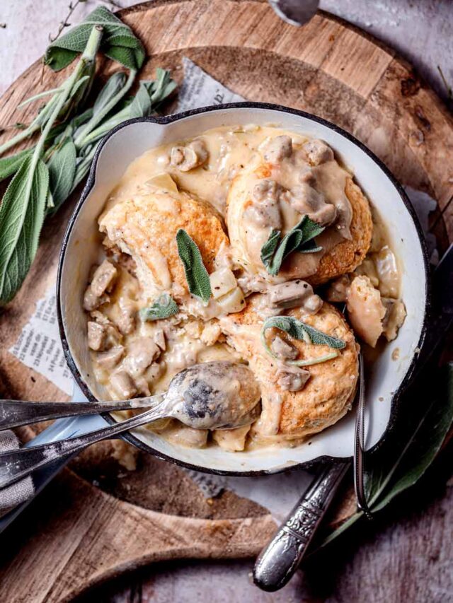 Flat lay shot of a plate of Vegan Biscuits and Gravy with a pair of spoon and fork on the lower edge of the plate