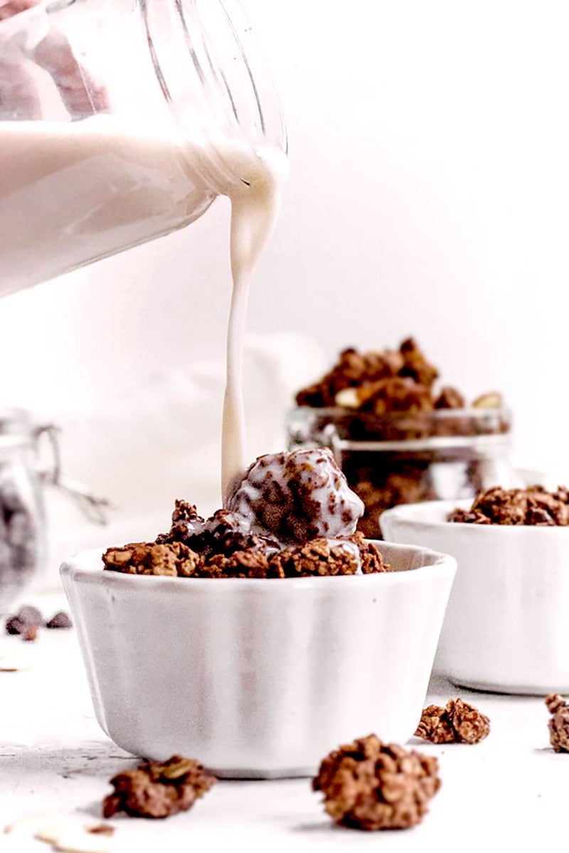 dark chocolate granola with almond butter in a white bowl.