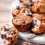 banana blueberry oat muffins with a streusel topping on a marble cutting board.