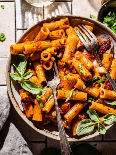 coconut milk pasta sauce on rigatoni with silver forks resting in the bowl.