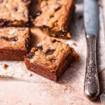 a sliced square of protein blondies resting next to a vintage silver knife.