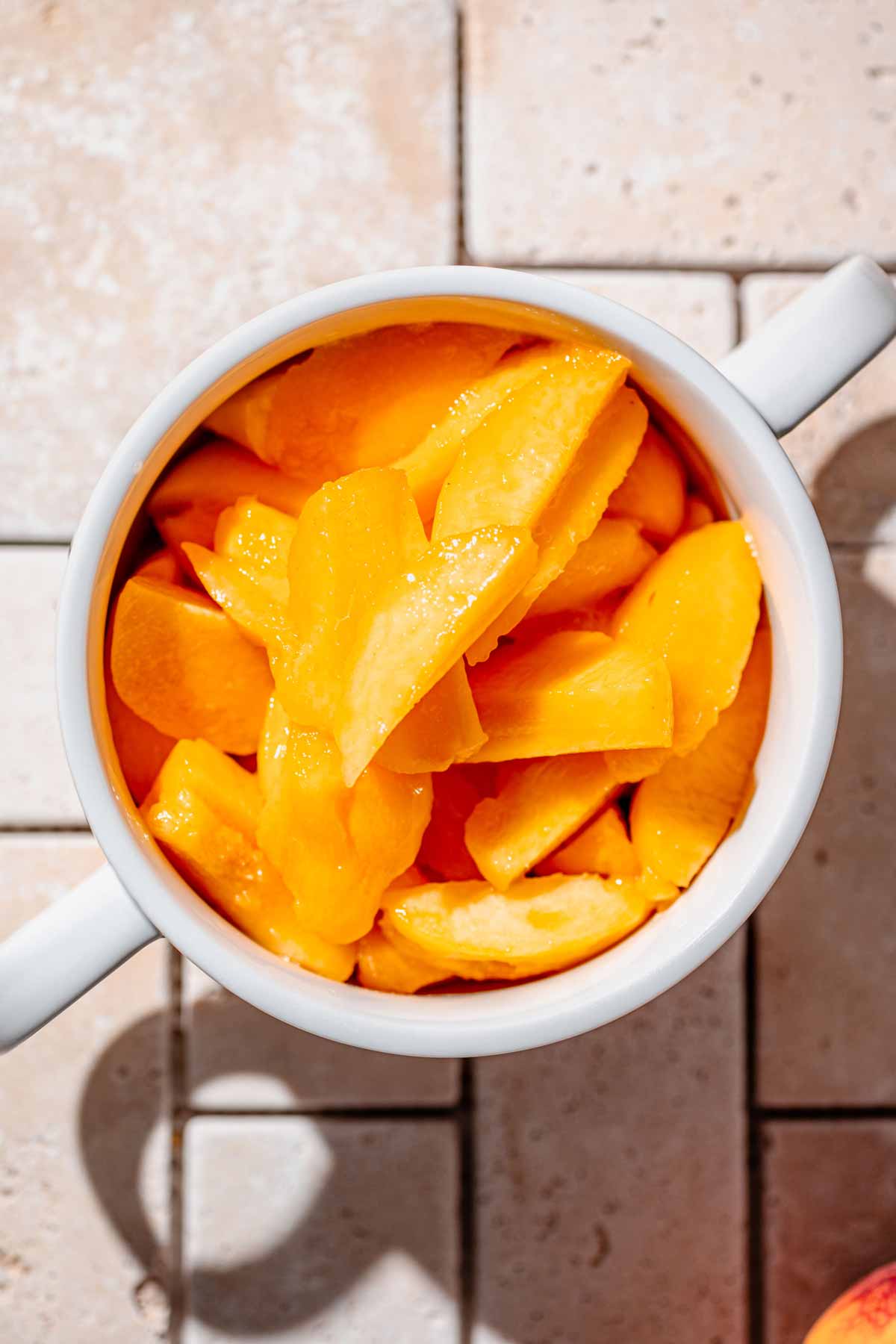 sliced and peeled peaches in a white bowl.