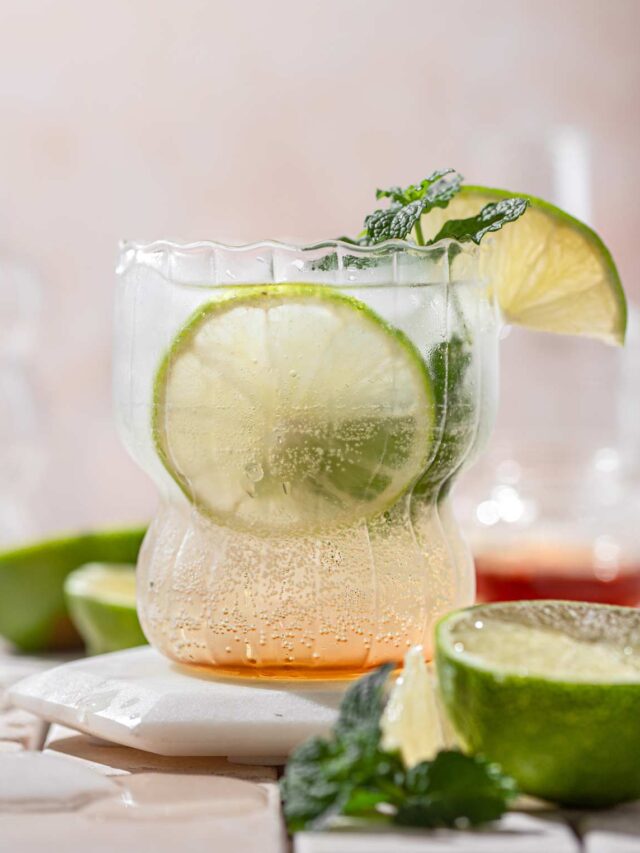 Simple gin mojito in a glass with a sprig on mint and a lime wedge.