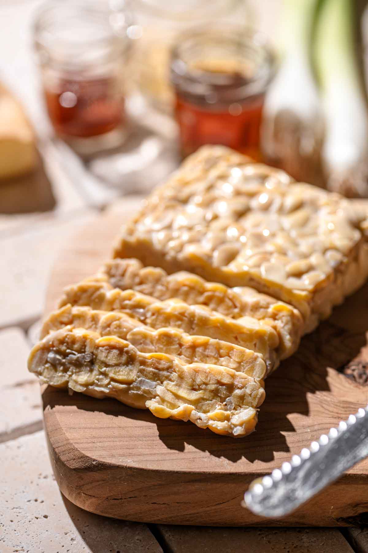 a block of sliced tempeh on a wood cutting board.