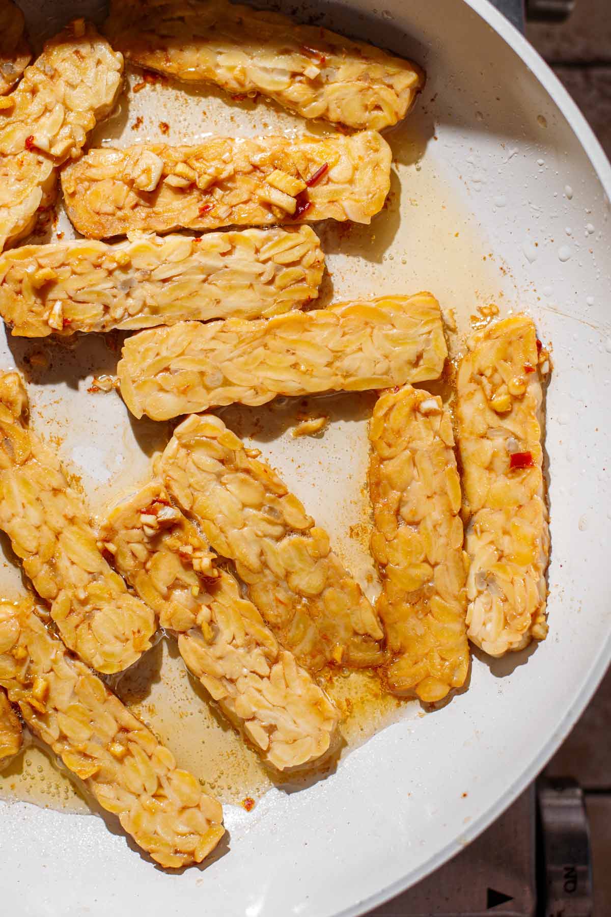 a white pan with slices of marinated tempeh.