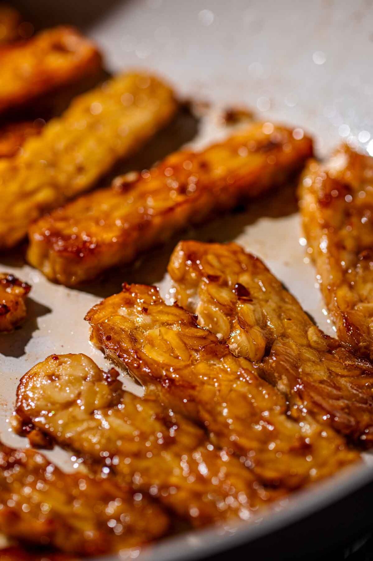 tempeh being fried in a pan.