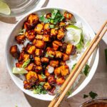 a white bowl filled with garlic lime tofu that has been pan-fried and tossed in a sticky sauce.