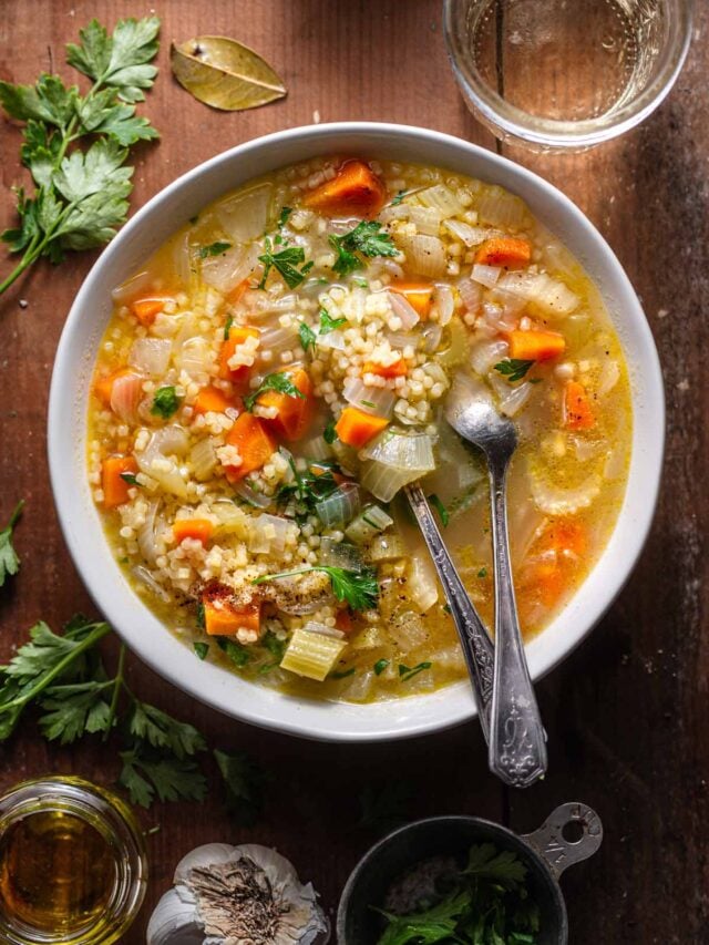 simple Italian pastina soup in a white bowl on a rustic wooden surface.