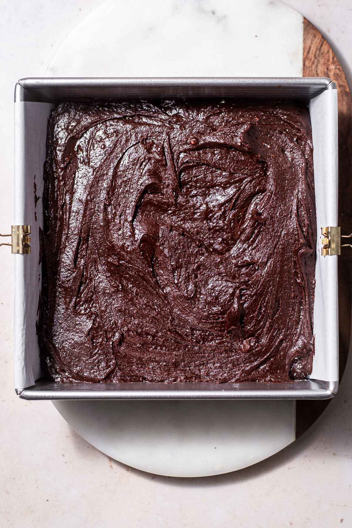 eggless brownie batter in a metal pan with parchment paper.