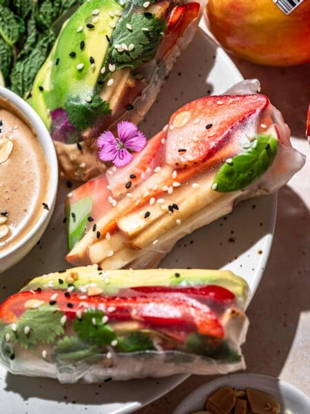 vegan summer rolls topped with sesame seeds on a white plate.