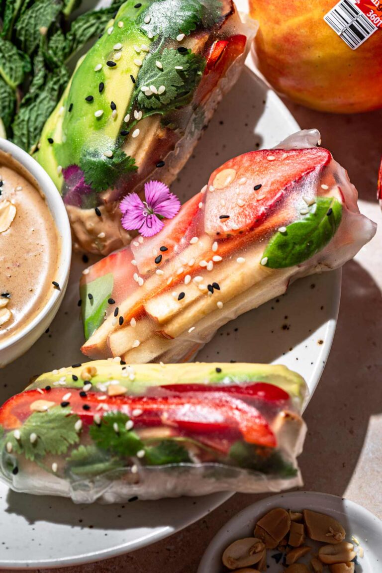 vegan summer rolls topped with sesame seeds on a white plate.