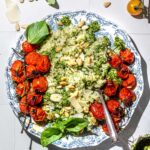 A plate of pesto rice with roasted cherry tomatoes on the vine.