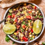 a white ceramic bowl filled with the creamy vegan corn and black bean salad.