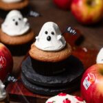 a cupcake with frosting in the shape of a ghost holding a flag that reads 'boo'.