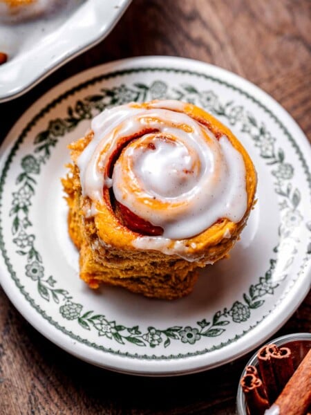a vegan pumpkin cinnamon roll on a dessert plate.