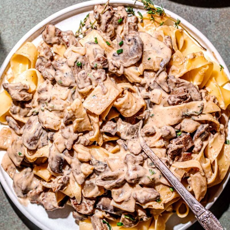 a plate of creamy vegan beef stroganoff with a silver fork.