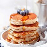thick and fluffy oat milk pancakes with syrup and berries.