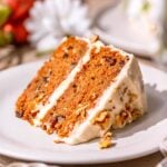 a slice of vegan carrot cake on a ceramic plate with cream cheese frosting.