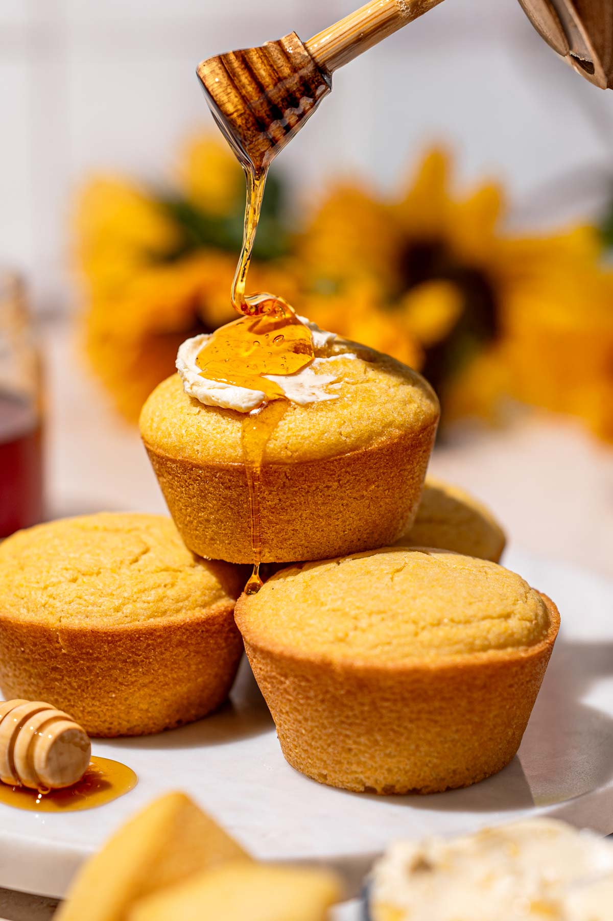 a stack of cornbread muffins with a drizzle of vegan honey and a smear of dairy-free butter.
