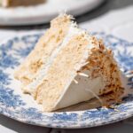 a slice of vegan coconut cake on a blue plate.