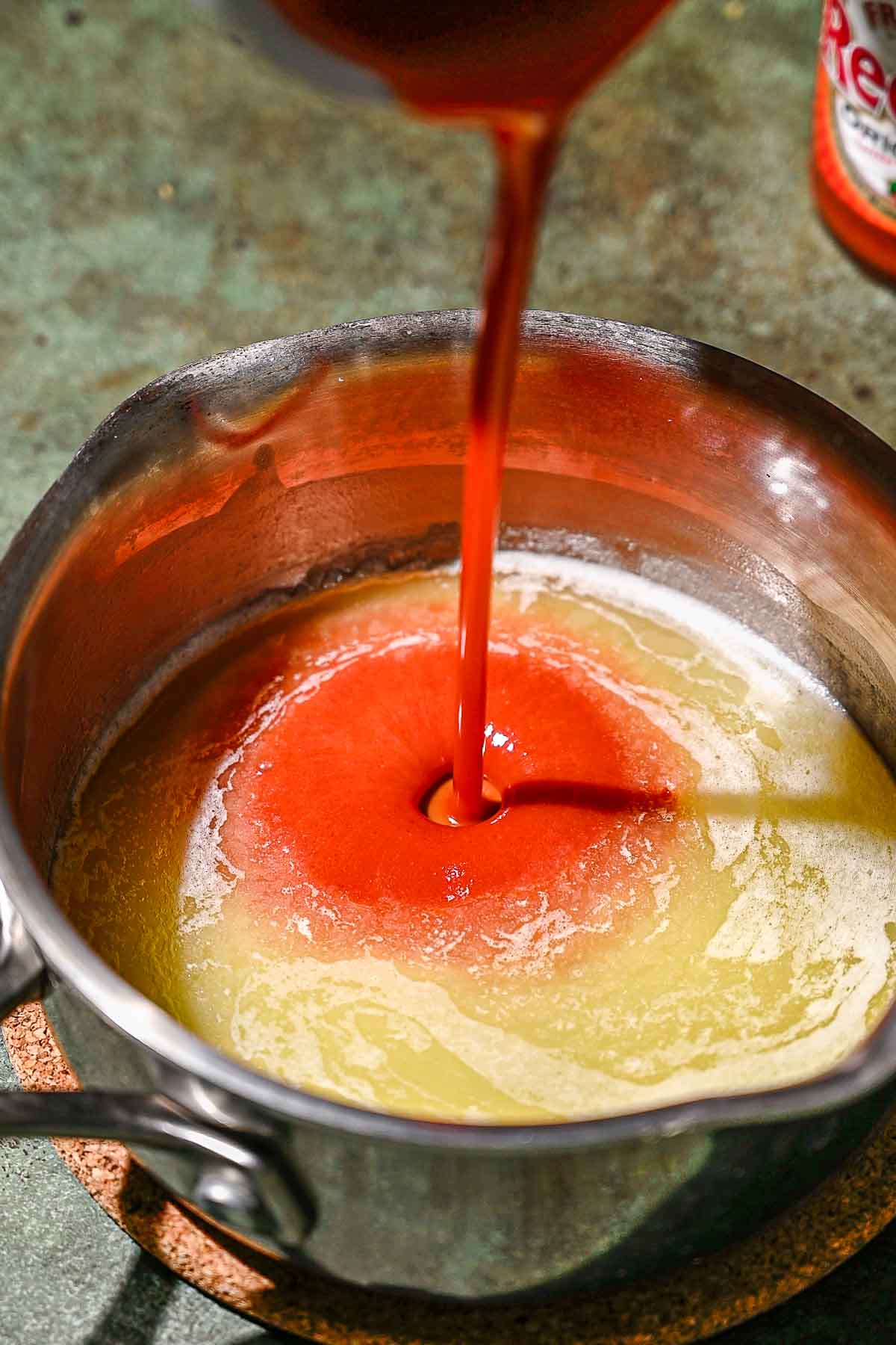 hot sauce being poured into melted vegan butter.