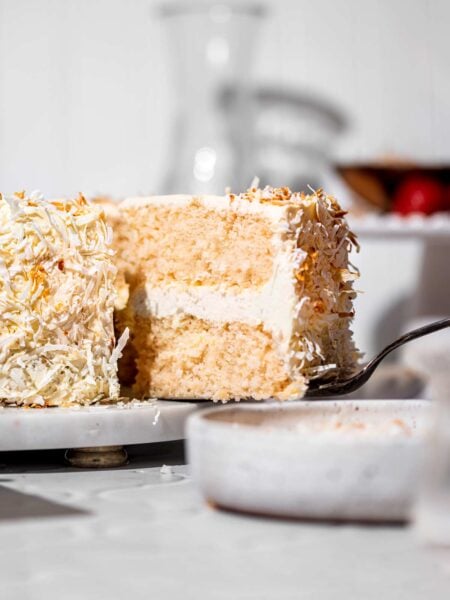 a slice of vegan coconut cake on an antique spatula.