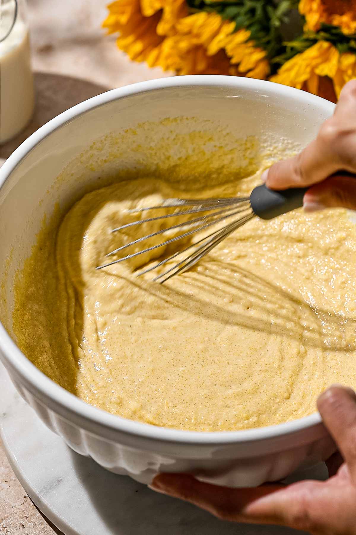 a hand whisking the wet ingredients into the dry ingredients.