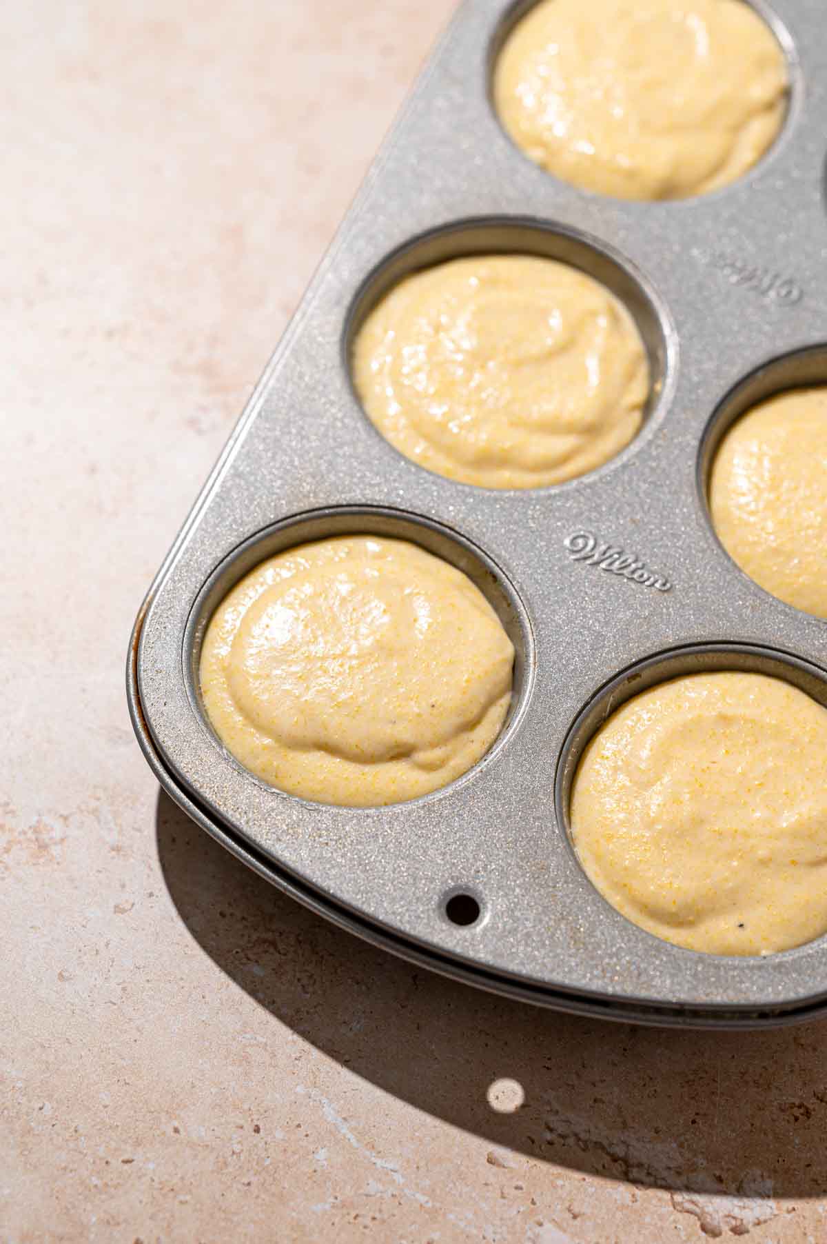 a filled metal muffin pan with the vegan cornbread batter.