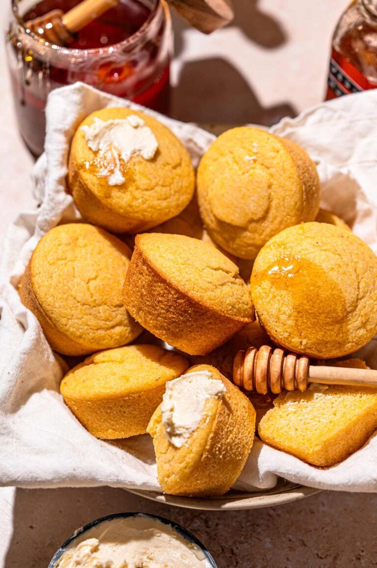a bowl lined with a linen cloth filled with vegan cornbread muffins.
