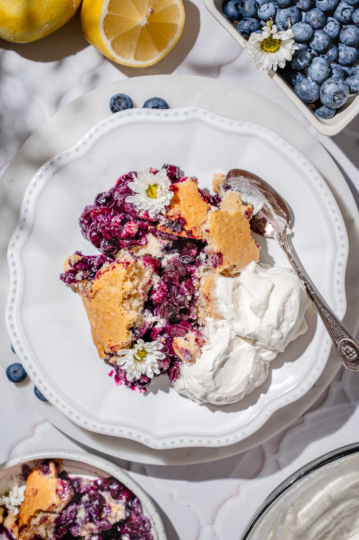 vegan berry cobbler scooped on a white plate with whipped cream.