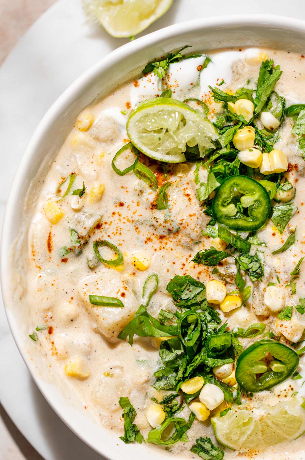 a close up image of the vegan corn chowder showing the texture of the creamy potatoes and toppings.