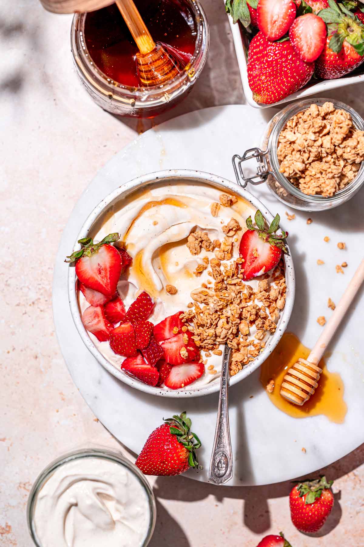 a ceramic bowl with homemade high protein dairy free yogurt topped with berries and granola.