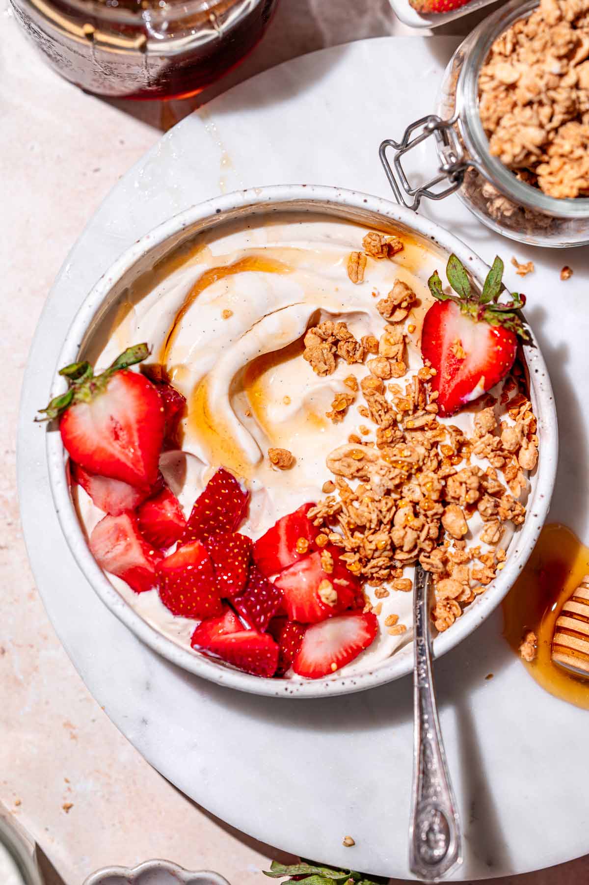 a ceramic bowl with homemade high protein dairy free yogurt topped with berries and granola.
