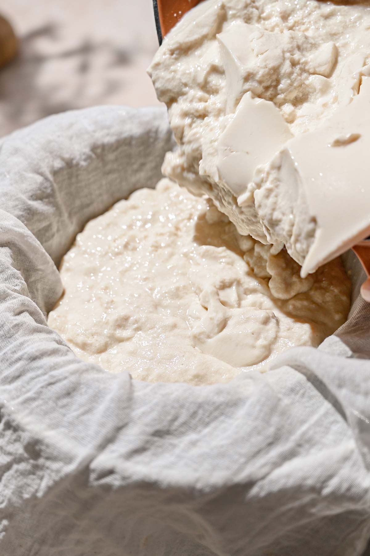 pouring the dairy-free yogurt into a cheesecloth.