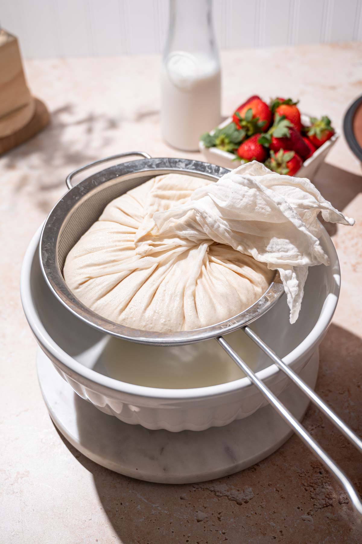 straining the vegan yogurt in a cheesecloth.