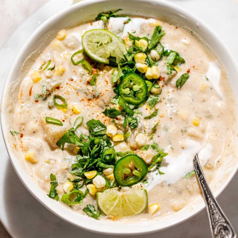 a bowl of creamy vegan corn chowder with potatoes, cilantro and lime.