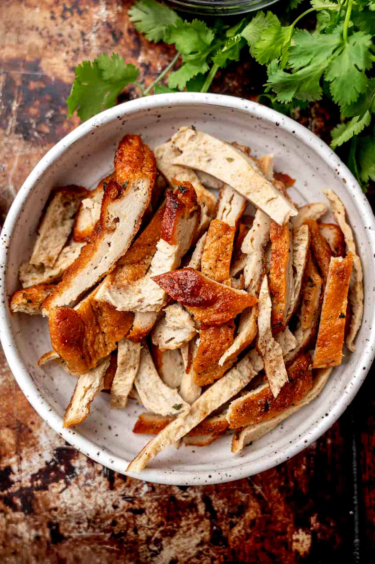 baked vegan chicken cut in strips in a white bowl.