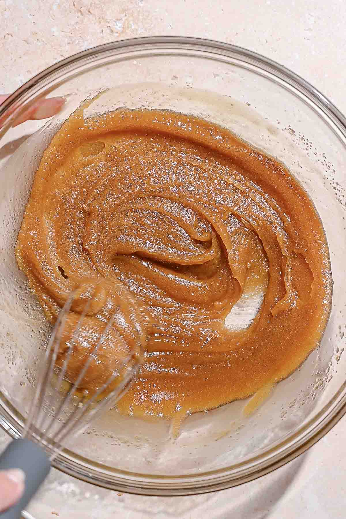 melted vegan butter and brown sugar being whisked together in a glass bowl.
