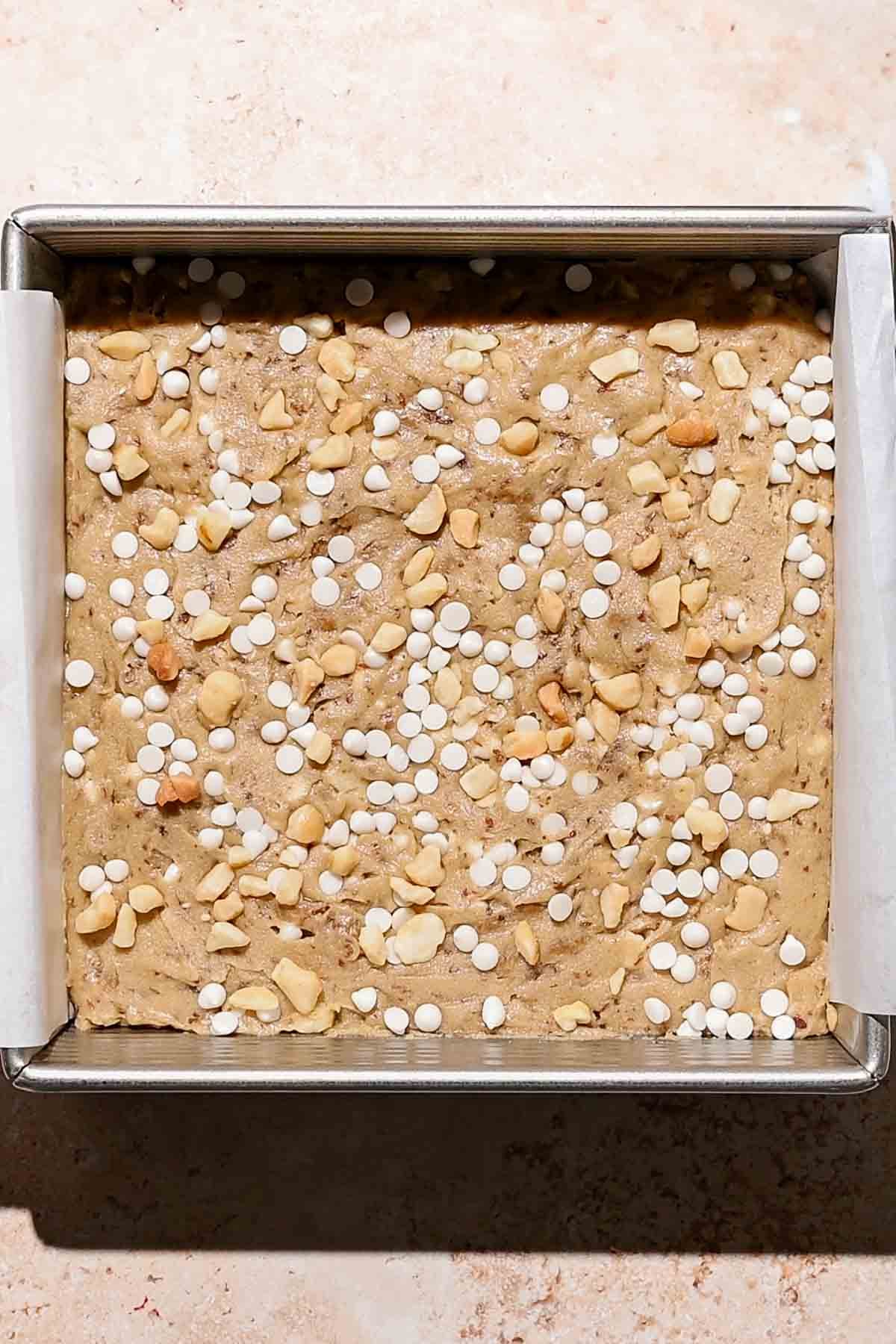 the blondie batter with white chocolate chips and macadamia nuts on top.