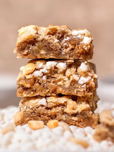 slices of vegan blondies with white chocolate chips stacked on each other.