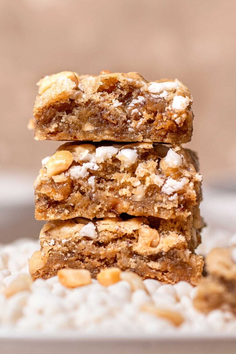 slices of vegan blondies with white chocolate chips stacked on each other.