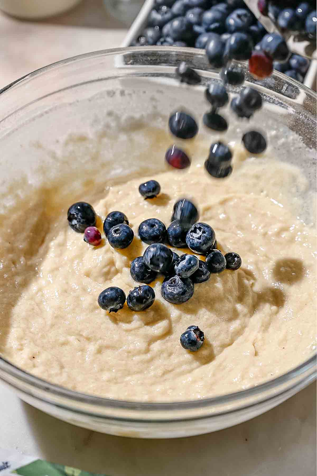 adding fresh blueberries to the cake donut batter.