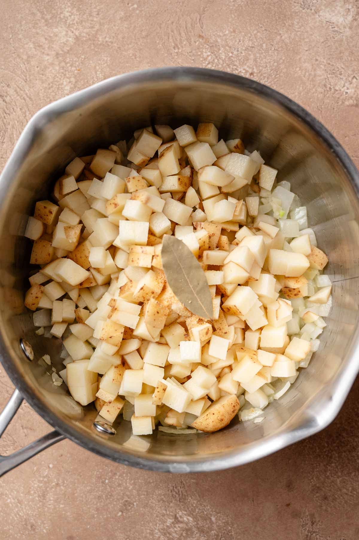 white potatoes and spices in a stainless steel pot with onion.