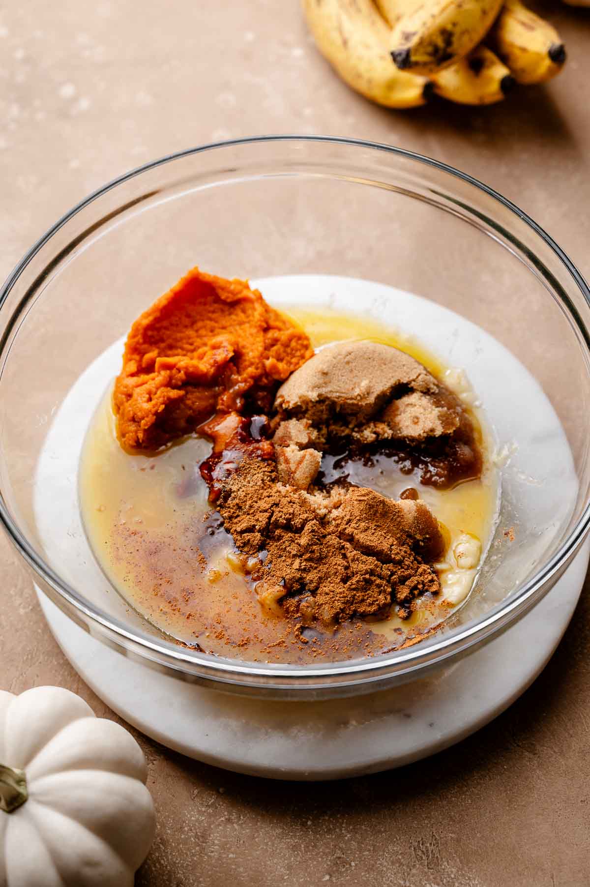 wet ingredients like brown sugar, mashed banana, pumpkin puree and vegan butter in a glass bowl.