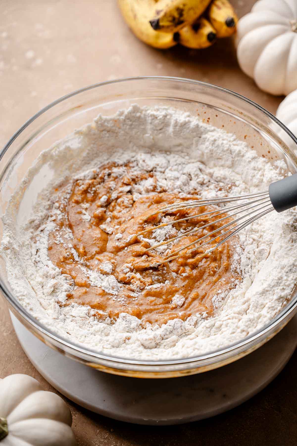 dry ingredients being whisked into the wet ingredients for the vegan pumpkin banana bread.