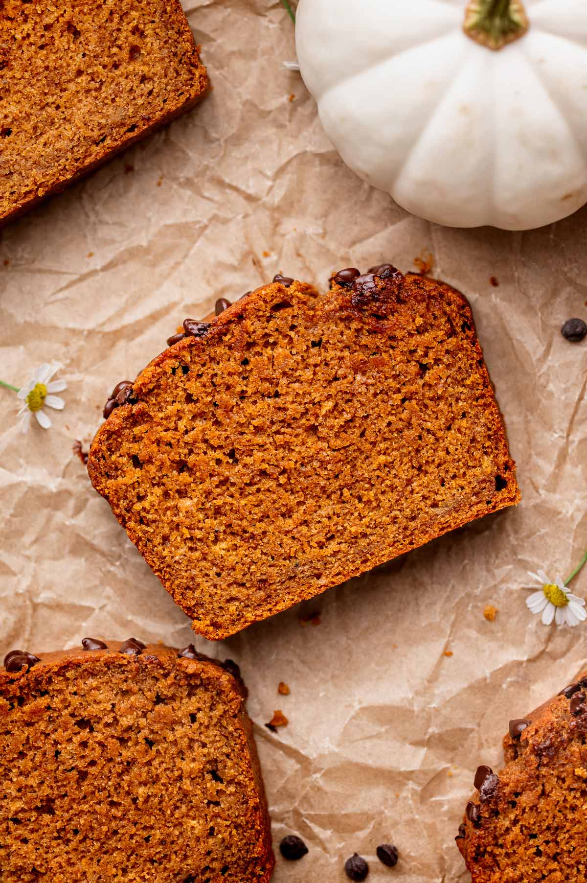 a sliced of the vegan pumpkin banana bread on crumpled brown parchment paper. 