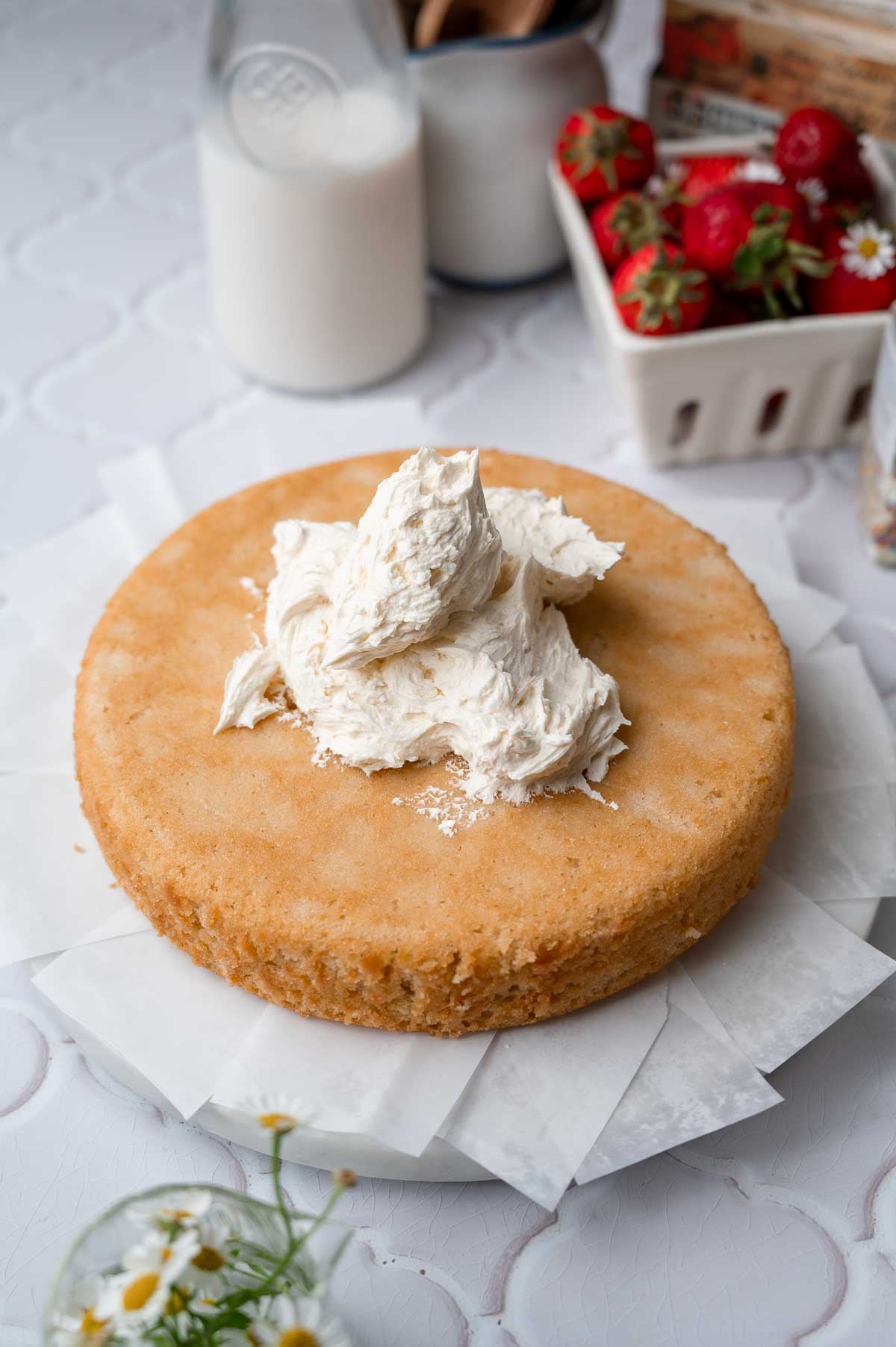a layer of vanilla cake on a marble stand with a dollop of vanilla frosting on top.